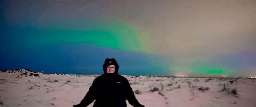 Meryl Salerno standing beneath the northern lights